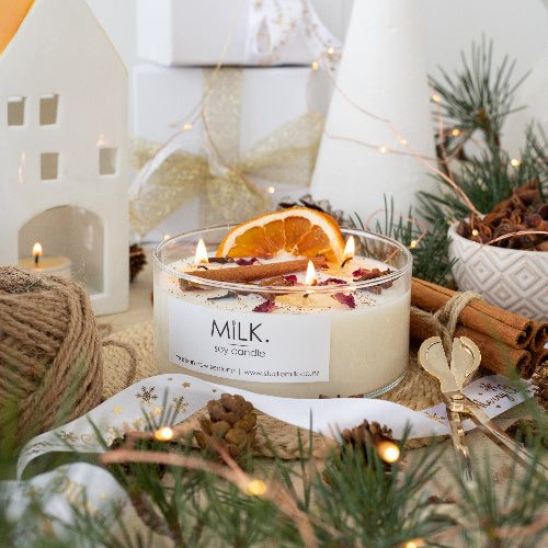 Candle with decorative elements on a table, featuring the brand 'MILK'.