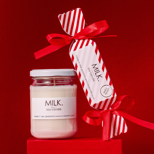 Soy tea light with a red ribbon and cracker packaging on a red background