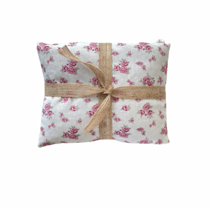 Floral-patterned fabric wheat bag with a brown ribbon on a white background