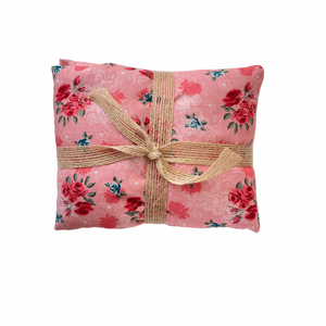 Pink floral fabric wheat bag with a brown ribbon on a white background