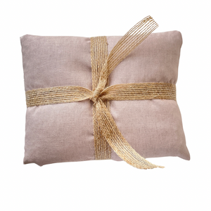 Dusky pink wheat bag with a gold ribbon on a white background